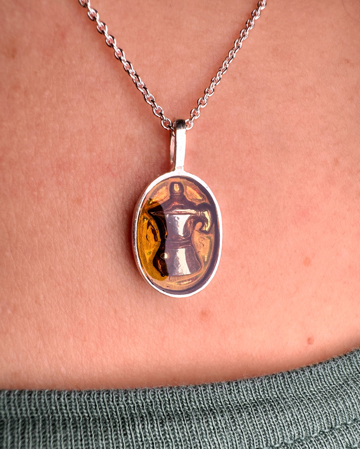 Silver necklace with oval amber enamel pendant featuring a moka pot design, worn on the neck