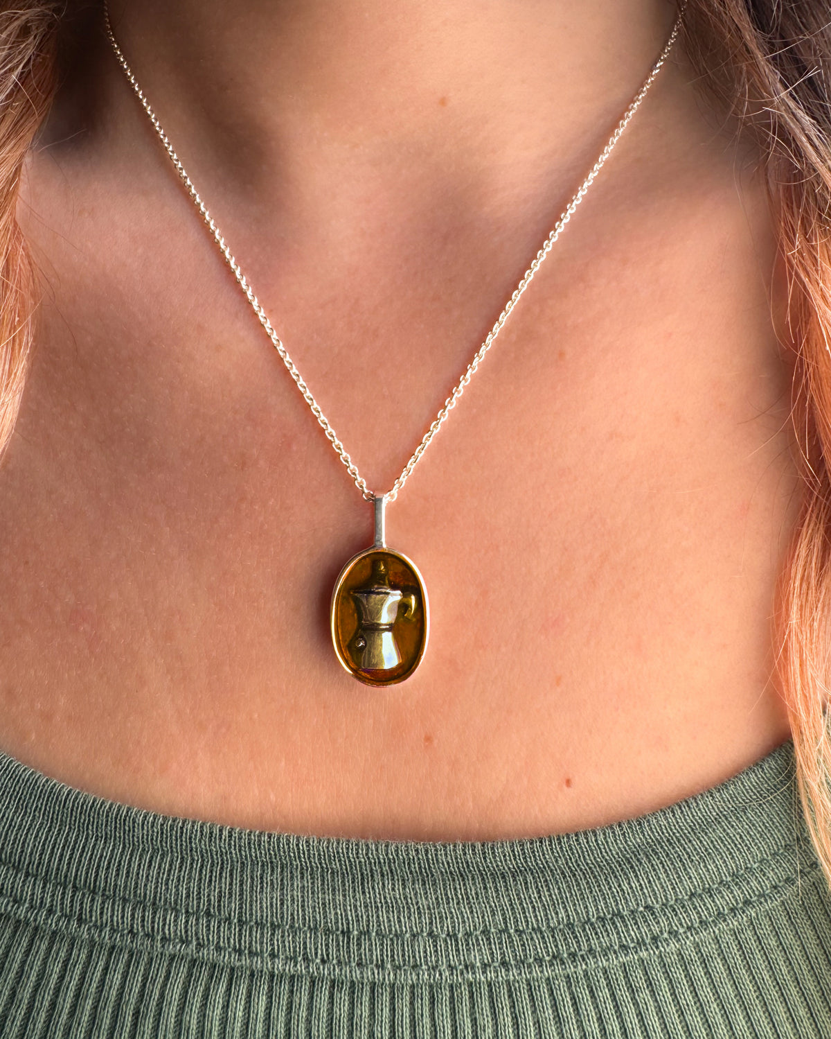 Silver necklace with oval amber enamel pendant featuring a moka pot design, worn on the neck