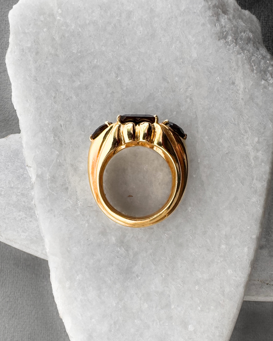 Gold plated ring with smoky quartz gemstones on a stone surface